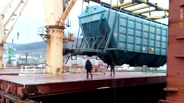 Moving freight railway car in the port by a port crane. Cargo lifting operations. Industrial port. — Stock Video