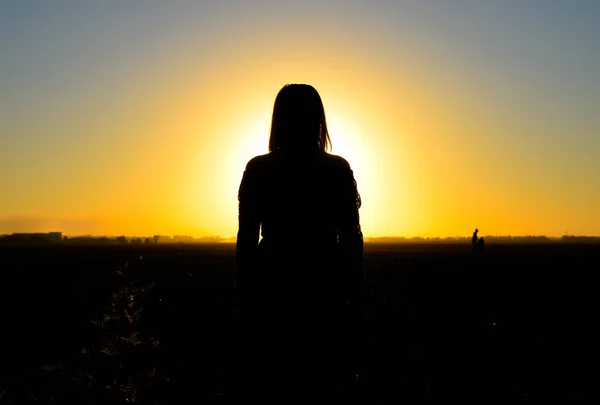 The figure of a woman at sunset. Black silhouette of a woman.