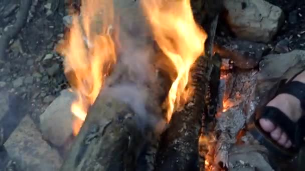 Verbranding van hout in het vuur en verwarm de voeten rond het vuur. — Stockvideo