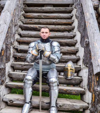 Knight in the armor on the wooden steps. Knightly armor and weapon clipart