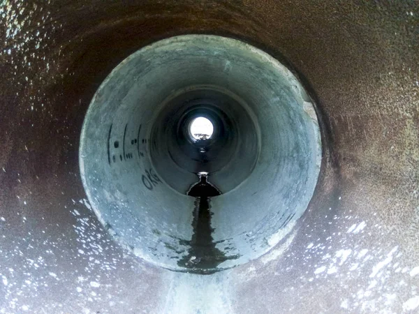 빗물을 도로 밑으로 흘려 보내는 터널. 파이프를 통해 보라 — 스톡 사진