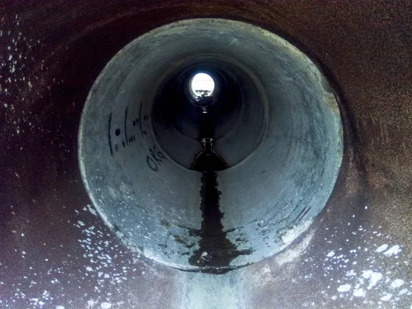 Tunnel per lo scarico dell'acqua piovana sotto la strada. Vista attraverso il tubo — Foto Stock