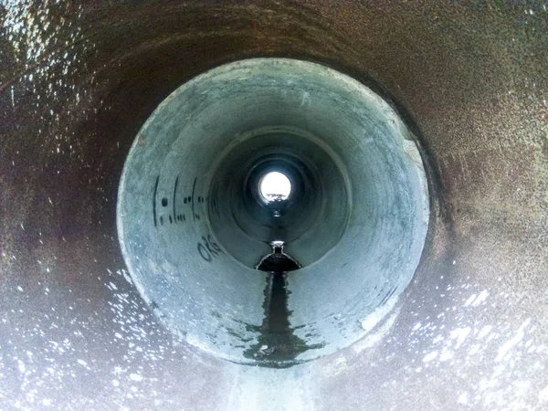 Túnel para drenagem de águas pluviais sob a estrada. Vista através do tubo — Fotografia de Stock