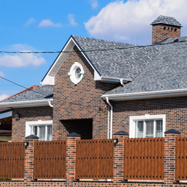 Asfalt shingle. Dekoratif bitüm Zona bir tuğla ev çatısında. Oluklu metal çit yapılmış