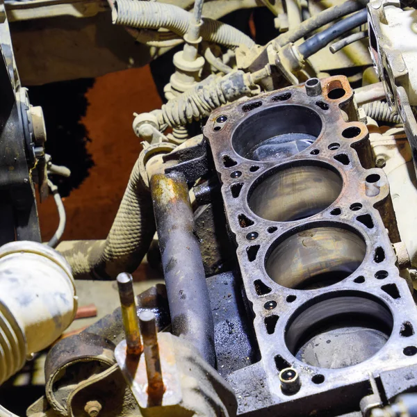 The cylinder block of the four-cylinder engine. Disassembled motor vehicle for repair. Parts in engine oil. Car engine repair in the service.