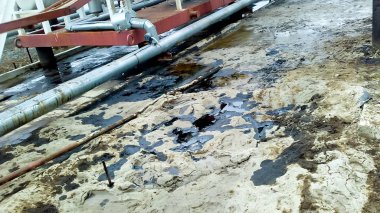 Dökülen petrol boru hatları ve proses ekipmanları yakınında kumlu topraklarında. Petrol sızıntıları işlemi ve onarım sırasında