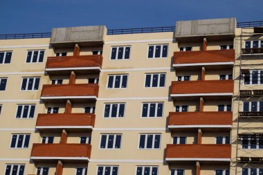 Yüksek katlı tuğla ev, kırmızı balkon ve sarı duvarlar duvar.