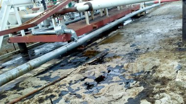 Dökülen petrol boru hatları ve proses ekipmanları yakınında kumlu topraklarında. Petrol sızıntıları işlemi ve onarım sırasında.