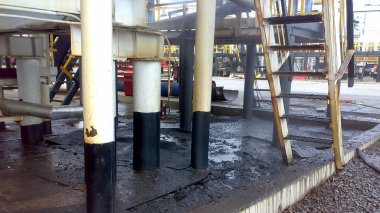Dökülen petrol boru hatları ve proses ekipmanları yakınında kumlu topraklarında. Petrol sızıntıları işlemi ve onarım sırasında.