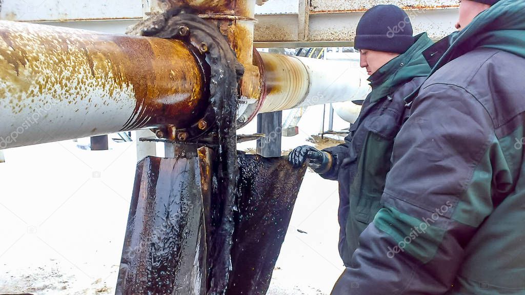 Liquidation of the oil spill. Locksmiths are engaged in eliminating oil leakage and repairing equipment. Workers liquidate the oil spill.