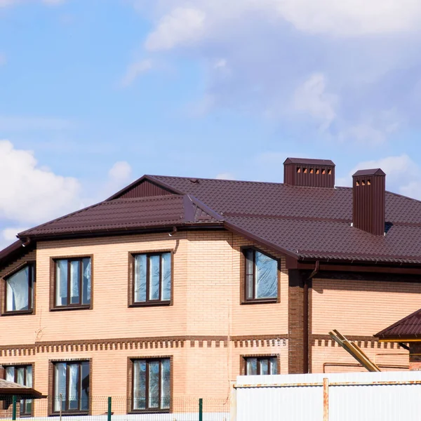Metal decorativo no telhado de uma casa de tijolos. Cerca feita de metal ondulado . — Fotografia de Stock