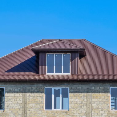 Evi kül blok. Plastik pencere ve oluklu levha çatısı olan ev. Çatı metal profil dalgalı şeklin üzerinde plastik penceresi olan ev