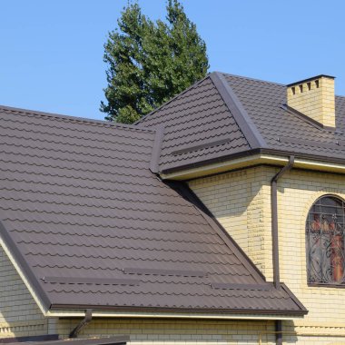 Sarı tuğla ve kahverengi oluklu çatı evi metalden yapılmış. Windows kafesler.