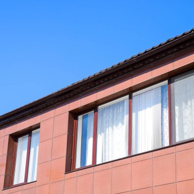 Plastik pencere ev ve bir akış sistemi çatıda. Plastik pencere ve oluklu levha kahverengi bir çatı ile ev