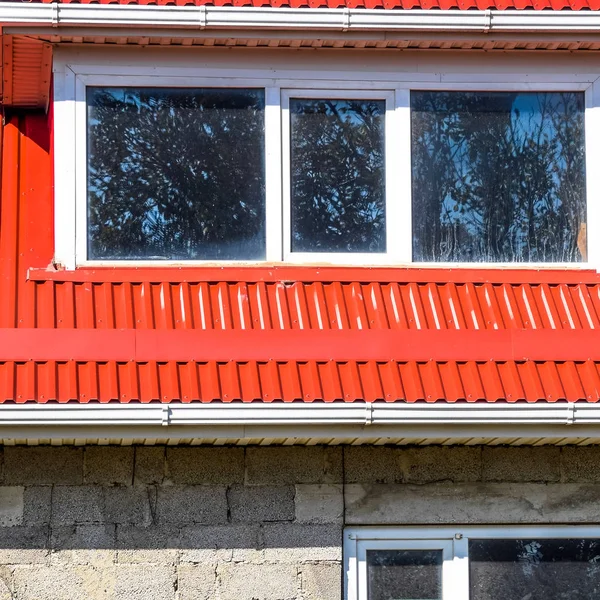 House of cinder block. House with plastic windows and a red roof of corrugated sheet