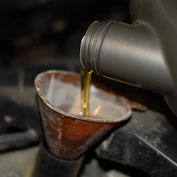 Oil change in the engine of the car. Filling the oil through the funnel. Car maintenance station. — Stock Photo, Image