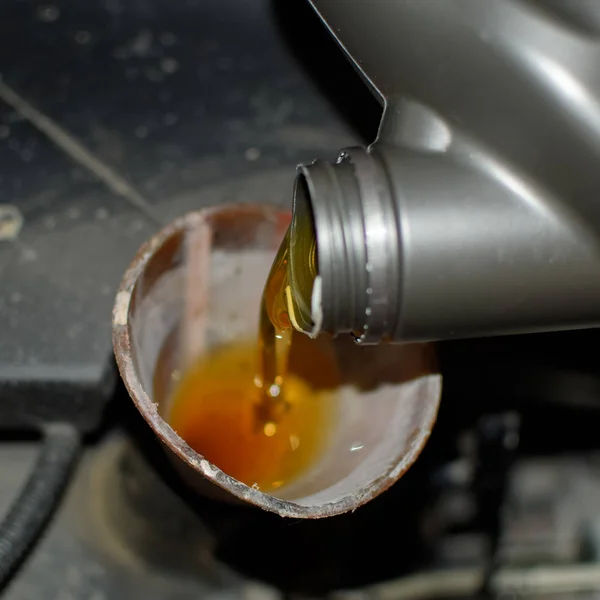 Oil change in the engine of the car. Filling the oil through the funnel. Car maintenance station.