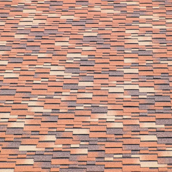 Roof from multi-colored bituminous shingles. Patterned bitumen shingles. — Stock Photo, Image