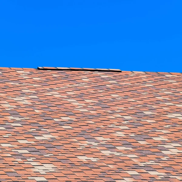 Roof from multi-colored bituminous shingles. Patterned bitumen shingles. — Stock Photo, Image