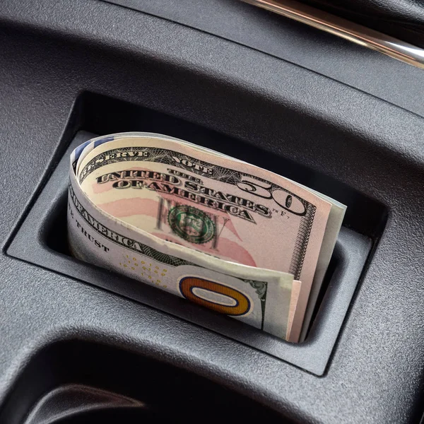 In der Nische der Mittelkonsole des Autos liegen mehrere Dollarnoten. das Geld im Auto — Stockfoto