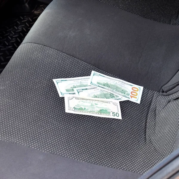 Auf dem Autositz liegen mehrere Dollarnoten. das Geld im Auto — Stockfoto