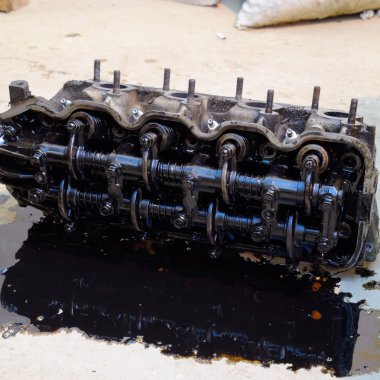 Silindir bloğunun başı. Silindir bloğunun başı tamir için motordan çıkarıldı. Motor yağının parçaları. Araç motoru tamiri serviste.