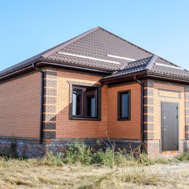 Plastik pencere ve oluklu levha çatısı olan ev. Çatı metal profil dalgalı şeklin üzerinde plastik penceresi olan ev