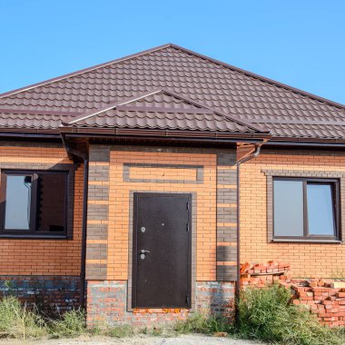 Plastik pencere ve oluklu levha çatısı olan ev. Çatı metal profil dalgalı şeklin üzerinde plastik penceresi olan ev