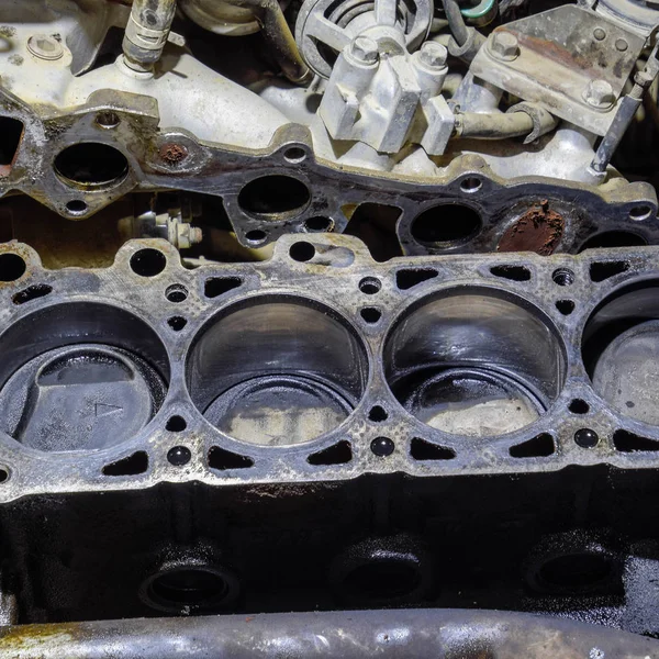 The cylinder block of the four-cylinder engine. Disassembled motor vehicle for repair. Parts in engine oil. Car engine repair in the service — Stock Photo, Image