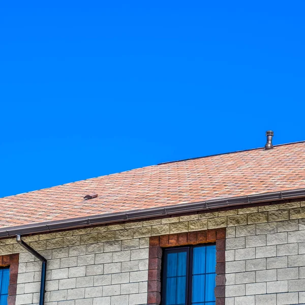 Het huis is gemaakt van beige baksteen, het dak is bedekt met bitumen shingles. Metalen kunststof ramen op het huis. — Stockfoto