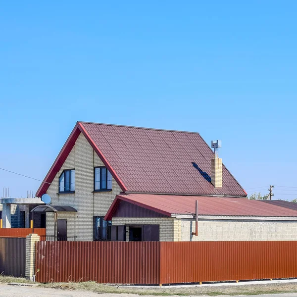 Дом с пластиковыми окнами и крышей из гофрированного листа. Крыша металлического профиля волнистой формы на доме с пластиковыми окнами — стоковое фото
