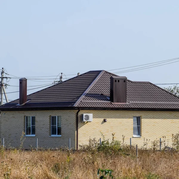 Das Haus mit Kunststofffenstern und einem Dach aus Wellblech — Stockfoto