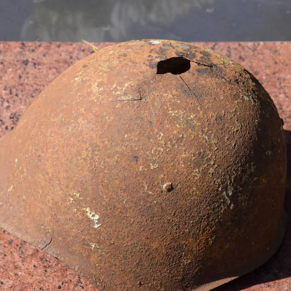 El casco protector del viejo soldado. El casco con un agujero. El casco de acero en el monumento — Foto de Stock