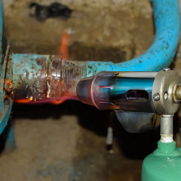 Heating a steel pipe with a blowtorch. The flame of a blowtorch — Stock Photo, Image