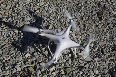 Drone Phantom 4 çakıl üzerinde duruyor ve pervaneleri döner. Drone uçuşunda hazırlık.