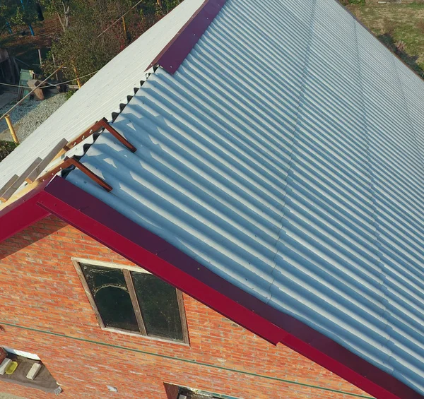 Κατασκευή της οροφής του σπιτιού, μια ξύλινη σκάλα στην οροφή με ένα γάντζο, οι γωνίες των πατίνια του κόκκινου μετάλλου προφίλ. — Φωτογραφία Αρχείου
