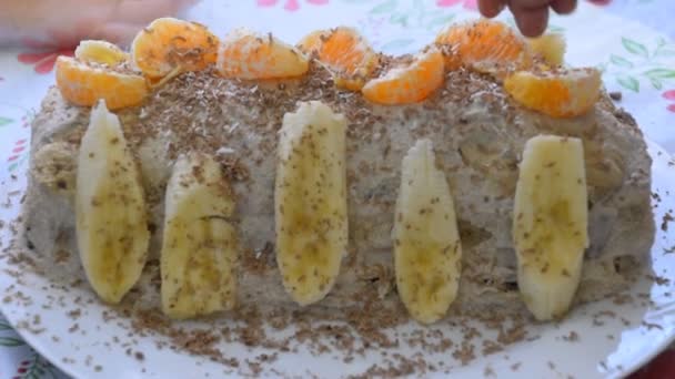 Cake met banaan en mandarijnen, besprenkeld met chocolade. — Stockvideo