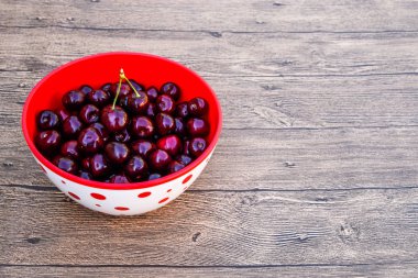 Plastik bardaktaki ahşap arka planda tatlı kirazlar. Olgun kırmızı tatlı kiraz
