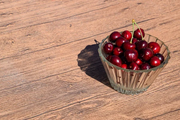 Berries of a sweet cherry in a glass bowl on a wood background. cherry merah manis matang — Stok Foto