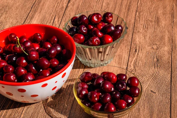 Berries of a sweet cherry on a wooden background in a plastic cup. Ripe red sweet cherry