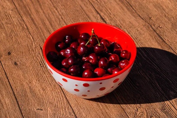 Berries of a sweet cherry on a wooden background in a plastic cup. Ripe red sweet cherry