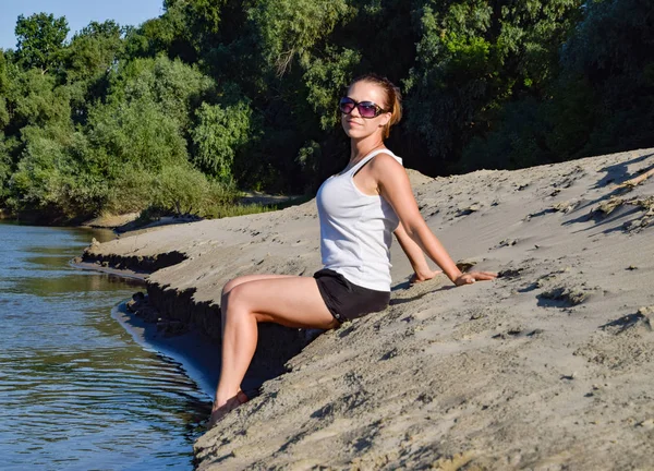 Девушка в белой футболке на песчаном берегу реки — стоковое фото