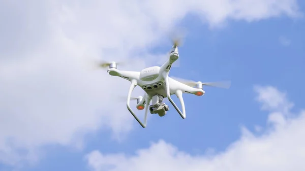 Vuelo quadrocopters blanco contra el cielo azul con nubes —  Fotos de Stock