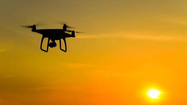 Silueta Quadrocopters contra el fondo de la puesta de sol. Drones voladores en el cielo nocturno —  Fotos de Stock