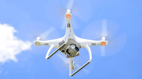 Drone DJI Phantom 4 in flight. Quadrocopter against the blue sky with white clouds. The flight of the copter in the sky.