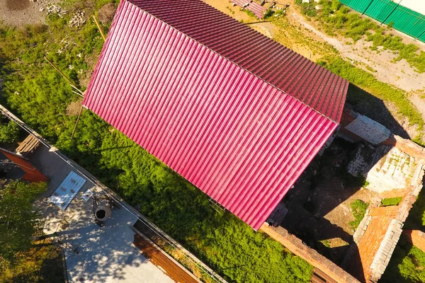 Дом с красной крышей из гофрированных металлических листов. Крыша из гофрированного металлического профиля. Металлическая плитка . — стоковое фото