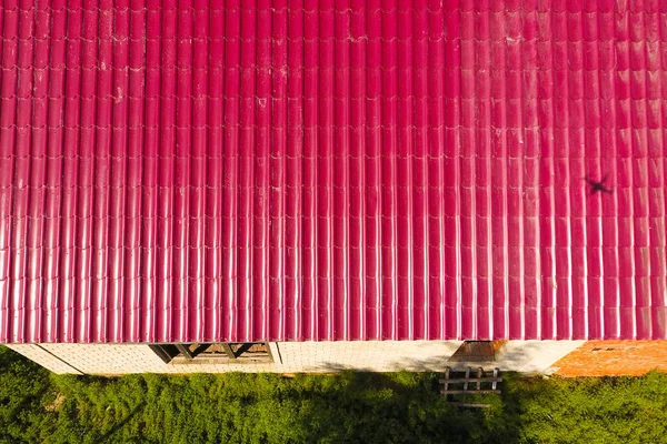 Una casa con un techo rojo hecho de chapas de metal corrugado. Techo de perfil de metal corrugado. Baldosas metálicas . — Foto de Stock