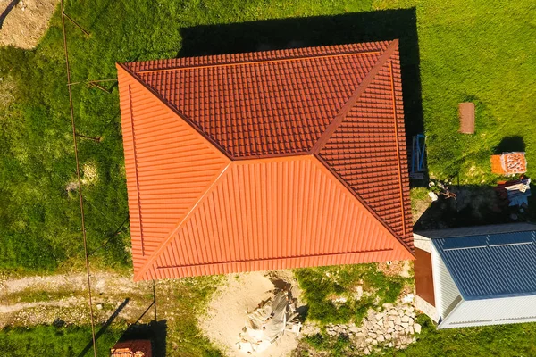 Woning met een oranje dak gemaakt van metaal, top uitzicht. Metalen profiel geschilderd gegolfd op het dak. — Stockfoto