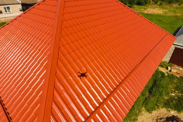 Σπίτι με πορτοκαλί στέγη κατασκευασμένη από μέταλλο, κορυφαία θέα. Μεταλλικά προφίλ ζωγράφισε κυματοειδές στη στέγη. — Φωτογραφία Αρχείου
