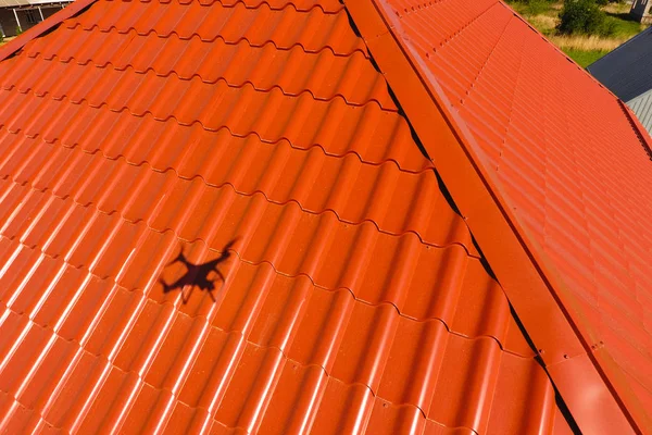Maison avec un toit orange en métal, vue sur le dessus. Profilé métallique peint ondulé sur le toit . — Photo